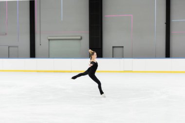 Buz arenasında uzanan elleri ile vücut giysisiyle buz pateni yapan profesyonel artistik patinajcı. 