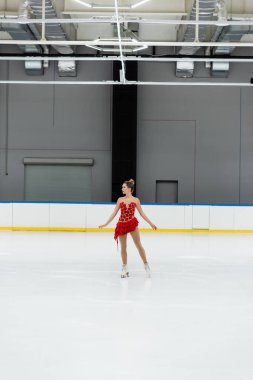 Profesyonel buz arenasında dans eden genç artistik patinajcı.