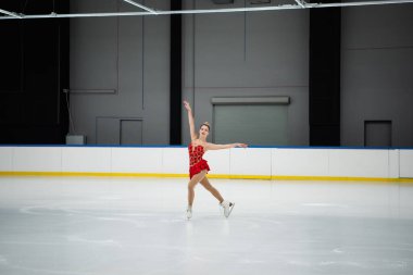 Profesyonel buz arenasında dans eden uzun elbiseli mutlu bir kadın.