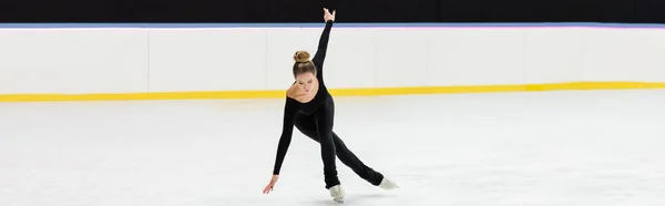 アイスアリーナ バナーで手を伸ばして黒のボディスケートでプロフィギュアスケートのフル長さ — ストック写真