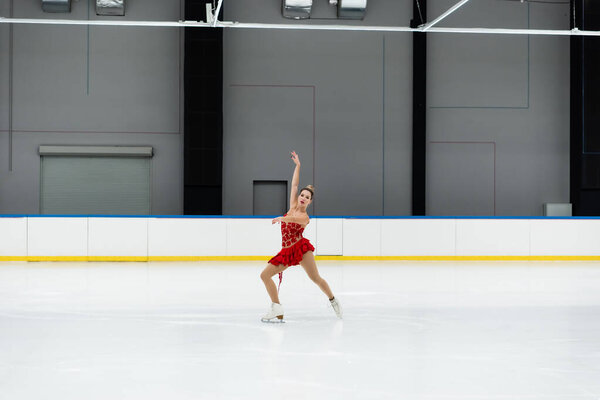 полная длина молодая женщина в платье фигура, исполняющая танец на профессиональной ледовой арене