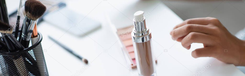 face foundation and cosmetic brushes near african american woman, banner 