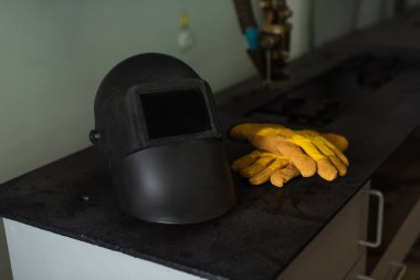 Fabrikadaki masada kaynak maskesi ve eldivenler. 