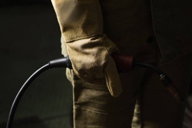 Eldivenli kaynak makinesi fabrikada kaynak makinesi tutuyor. 