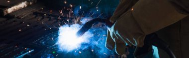 Cropped view of welder working with torch in factory, banner  clipart
