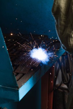 Cropped view of welder working with sparkling torch in factory  clipart