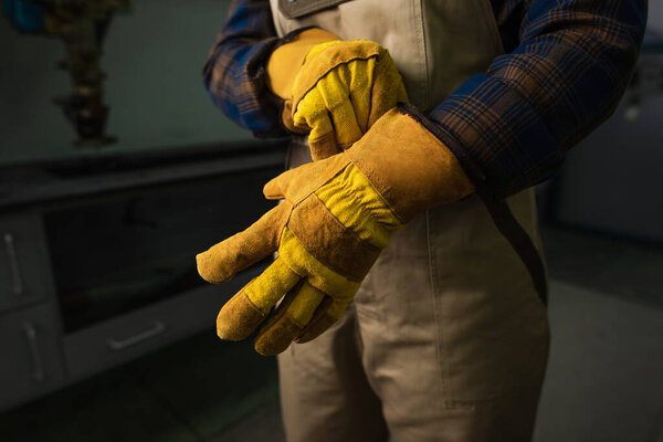 Cropped view of welder wearing gloves in factory 