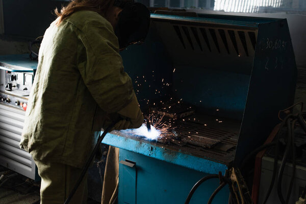 Brunette welder working with welding torch in factory 
