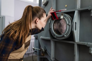 Fabrikadaki vakumlu lazer kaynak makinesine bakan kaynakçının yan görüntüsü 