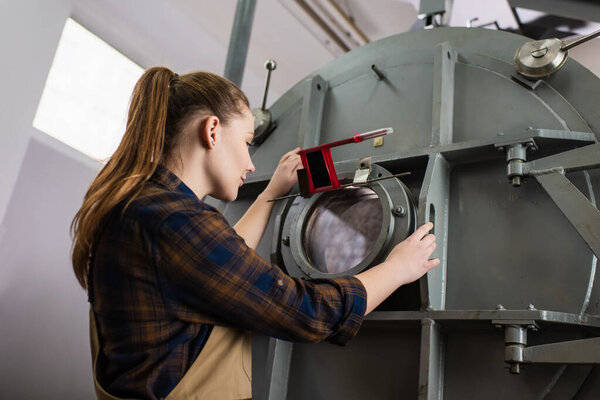 Low angle view of welder working with vacuum laser welding machine in factory 