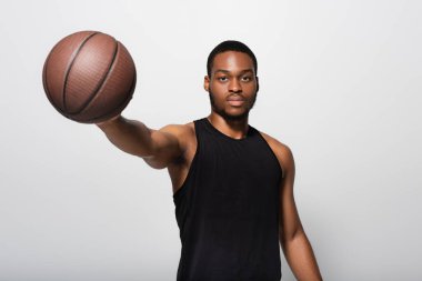 Genç Afrikalı Amerikalı oyuncu, elini uzatmış, basketbolu tutuyordu.