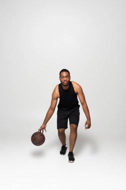 Gride basketbol oynayan kaslı Afrikalı Amerikalı adam.