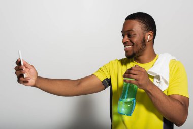 Kulağında kulaklığı olan neşeli Afro-Amerikan sporcusu Grey 'e selfie çekiyor.