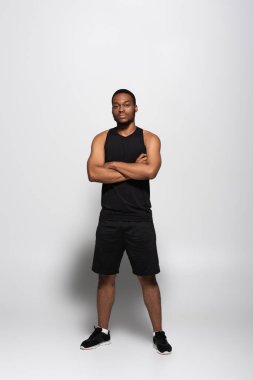 Askılı tişörtlü ve şortlu, gri kollu Afro-Amerikan sporcusu.