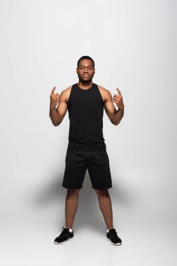 Uzun kollu tişörtlü Afro-Amerikan sporcusu ve gri üzerinde kaya işareti olan şortlu.