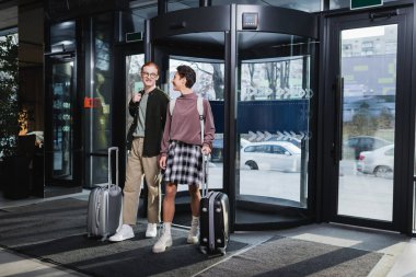 Otel lobisinde bavulları olan olumlu bir çift var. 