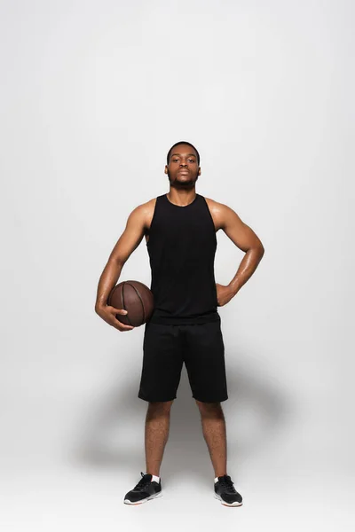 Pełna Długość Afrykańskiego Amerykańskiego Gracza Trzymającego Koszykówkę Stojąc Ręką Biodrze — Zdjęcie stockowe