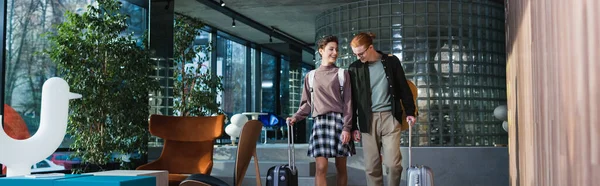 Young Couple Backpacks Suitcases Talking Hotel Lobby Banner — стоковое фото