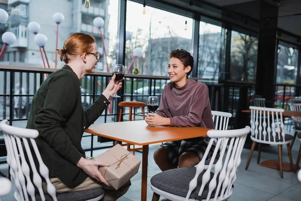 Young Man Holding Present Smiling Girlfriend Wine Hotel Cafe — стоковое фото