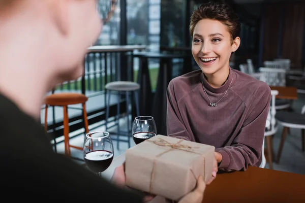 Excited Woman Holding Present Wine Blurred Boyfriend Hotel Cafe — Stock Photo, Image