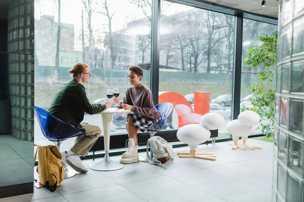 Glimlachende Vrouw Met Wijn Buurt Van Vriendje Rugzakken Modern Hotel — Stockfoto