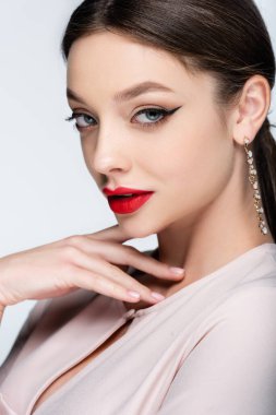 Küpeli güzel bir kadın gri renkli kameraya bakıyor.