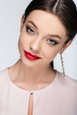 Gülümseyen ve küpe takan güzel bir kadın. Gri üzerinde yalnız poz veriyor.