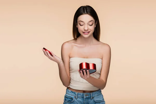 Joyful Young Woman Looking Heart Shaped Red Box Isolated Beige — Zdjęcie stockowe