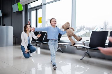 happy kid with teddy bear welcoming blurred father in airport  clipart
