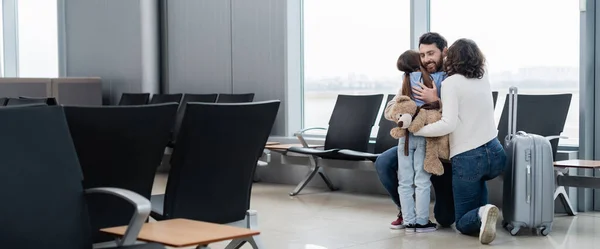 空港ラウンジバナーで抱き合っている愛情と幸せな家族 — ストック写真