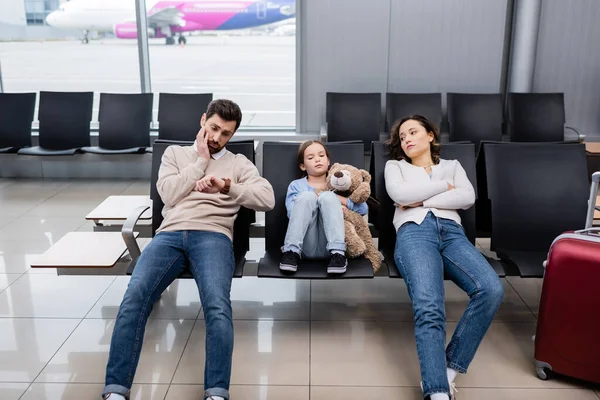 Verveelde Man Zoek Naar Horloge Buurt Van Dochter Vrouw Luchthaven — Stockfoto