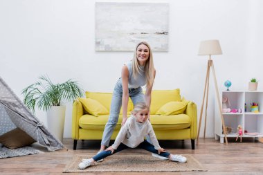 Parent smiling at camera near daughter at home 
