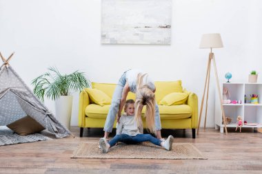 Woman touching smiling daughter while playing at home 