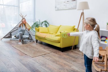 Blurred kid playing with slinky and mom at home 