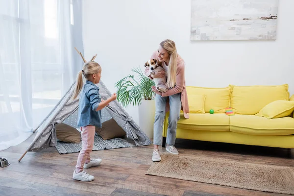 Happy Woman Holding Jack Russell Terrier Looking Daughter Home — Zdjęcie stockowe