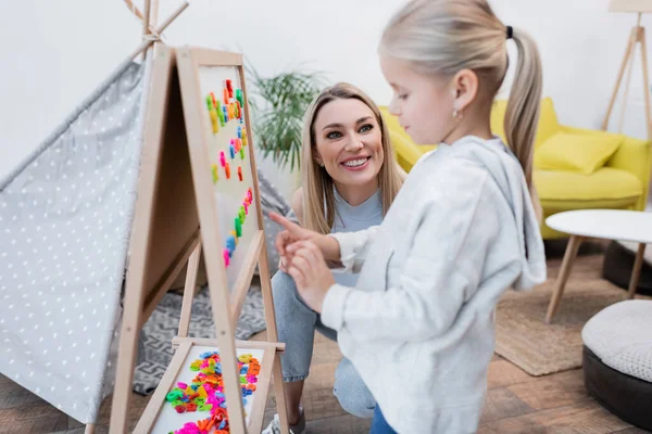 Mother Looking Blurred Daughter Pointing Magnetic Easel Home — Stok Foto