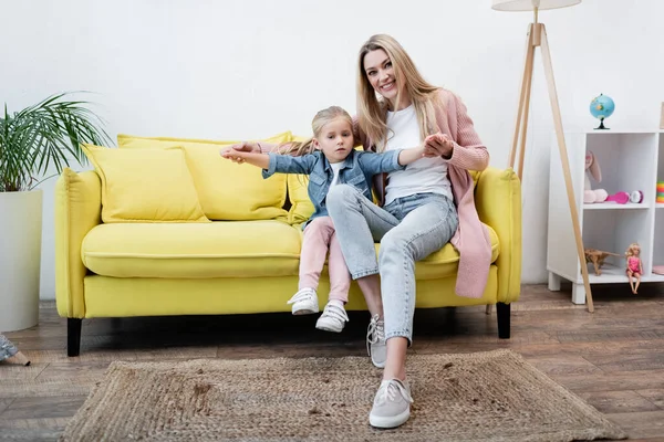 Smiling Mother Holding Hands Child Couch Home — Fotografie, imagine de stoc