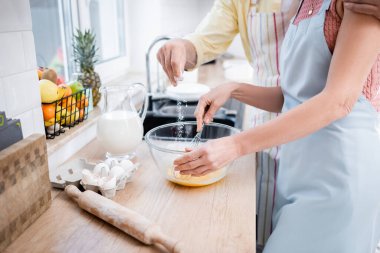 Karısı mutfakta yumurta pişirirken, adamın kaseye un döktüğü görüntüler. 