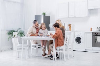 Dedeleri ve torunları modern mutfakta yapboz oynuyorlar.