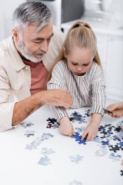 Son sınıf öğrencisi torunla yapboz oyunu oynuyor.