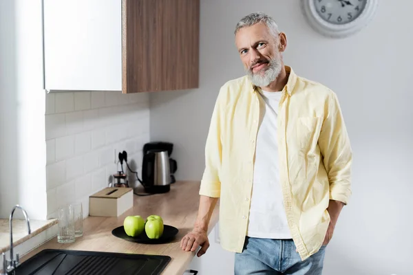 Lächelnder Älterer Mann Blickt Küche Die Kamera Neben Äpfeln — Stockfoto
