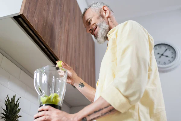 Visão Baixo Ângulo Homem Tatuado Positivo Derramando Frutas Liquidificador Cozinha — Fotografia de Stock