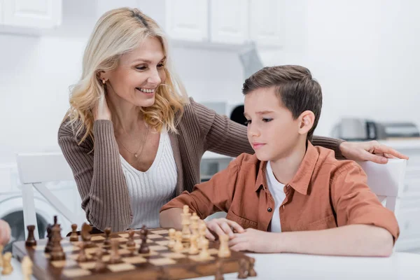 Frau Mittleren Alters Lächelt Neben Enkel Beim Schachspielen Küche — Stockfoto