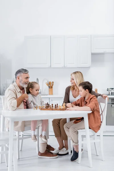 Happy Couple Playing Chess Grandchildren Kitchen — Stock Photo, Image