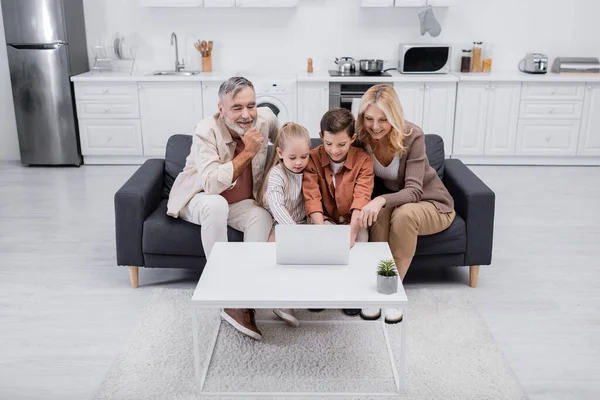 Kinder Mit Laptop Der Nähe Glücklicher Großeltern Auf Couch Küche — Stockfoto