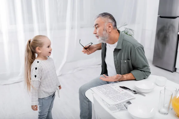 Gray Haired Man Holding Eyeglasses Pointing Hand While Talking Granddaughter — Stock Photo, Image