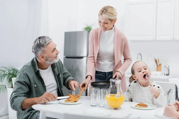 Mujer Alegre Que Sirve Panqueques Para Marido Durante Desayuno Con — Foto de Stock