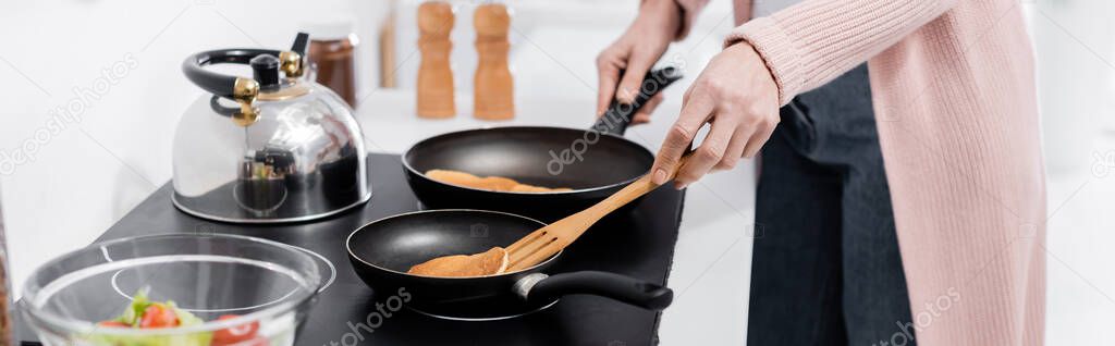 partial view of housewife cooking pancakes on frying pans, banner