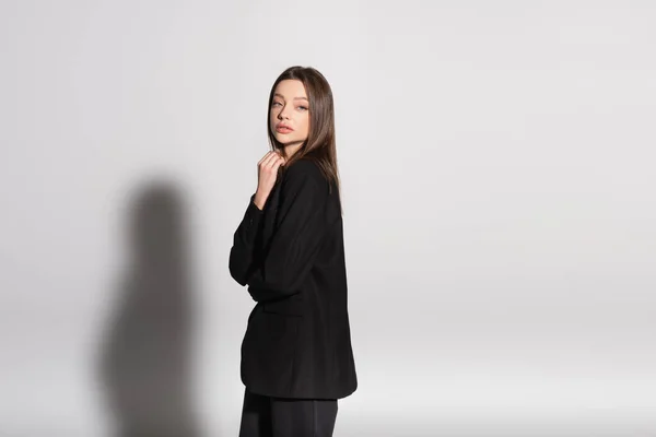 Young Woman Black Clothes Looking Camera While Standing Grey Shadow — Stock Photo, Image