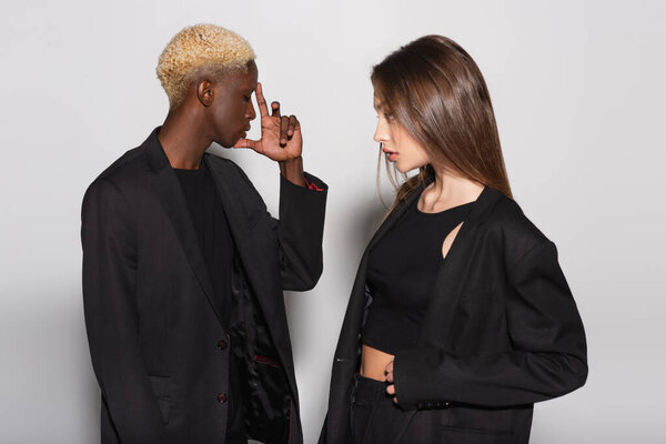 Американский блондин, держащийся за руку рядом со стильной брюнеткой на сером